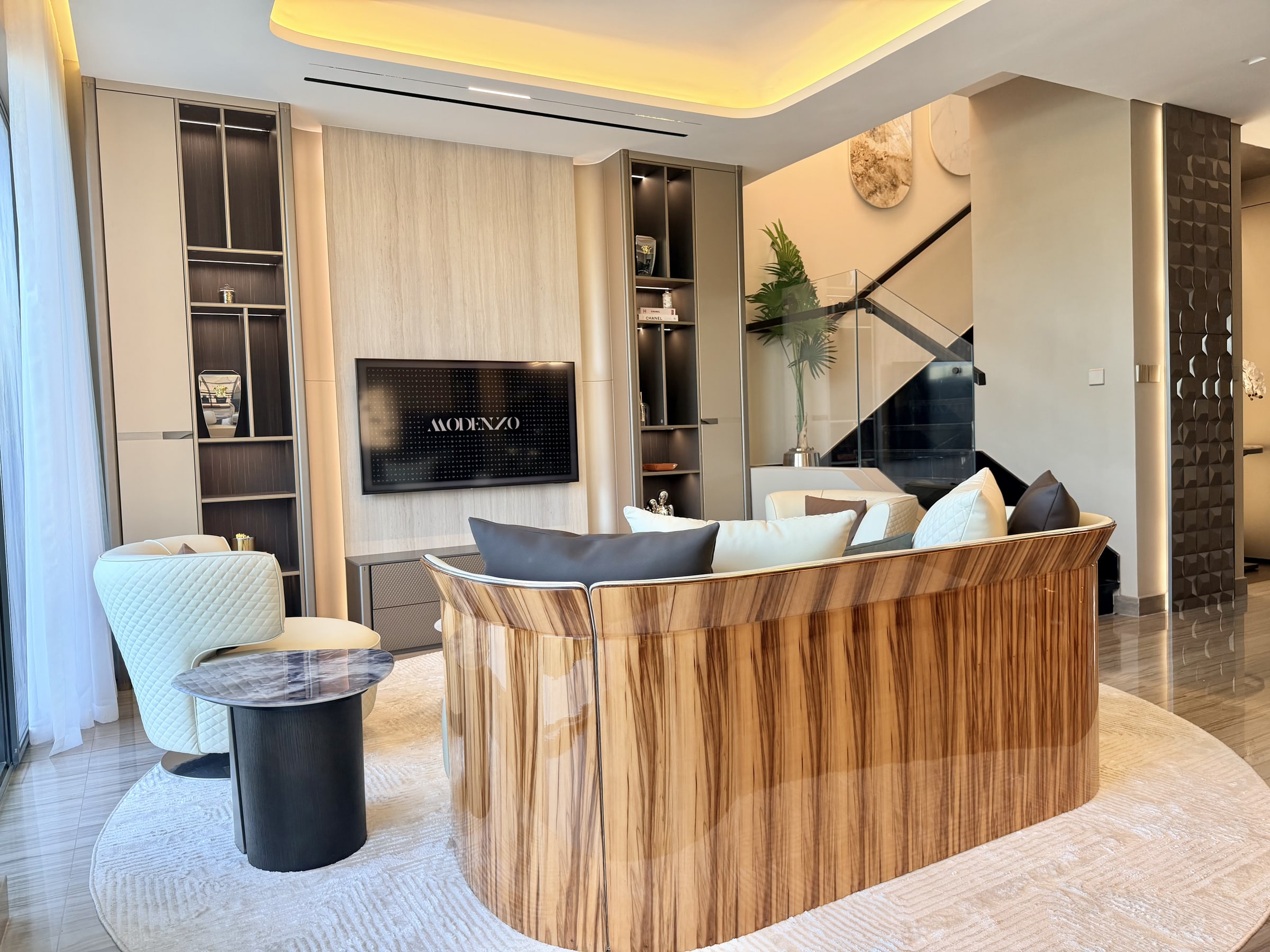 Curved high-gloss veneer sofa facing a custom media wall with ambient lighting in a Dubai living room, fitted by the team behind this kitchen renovation NOC approval Dubai guide