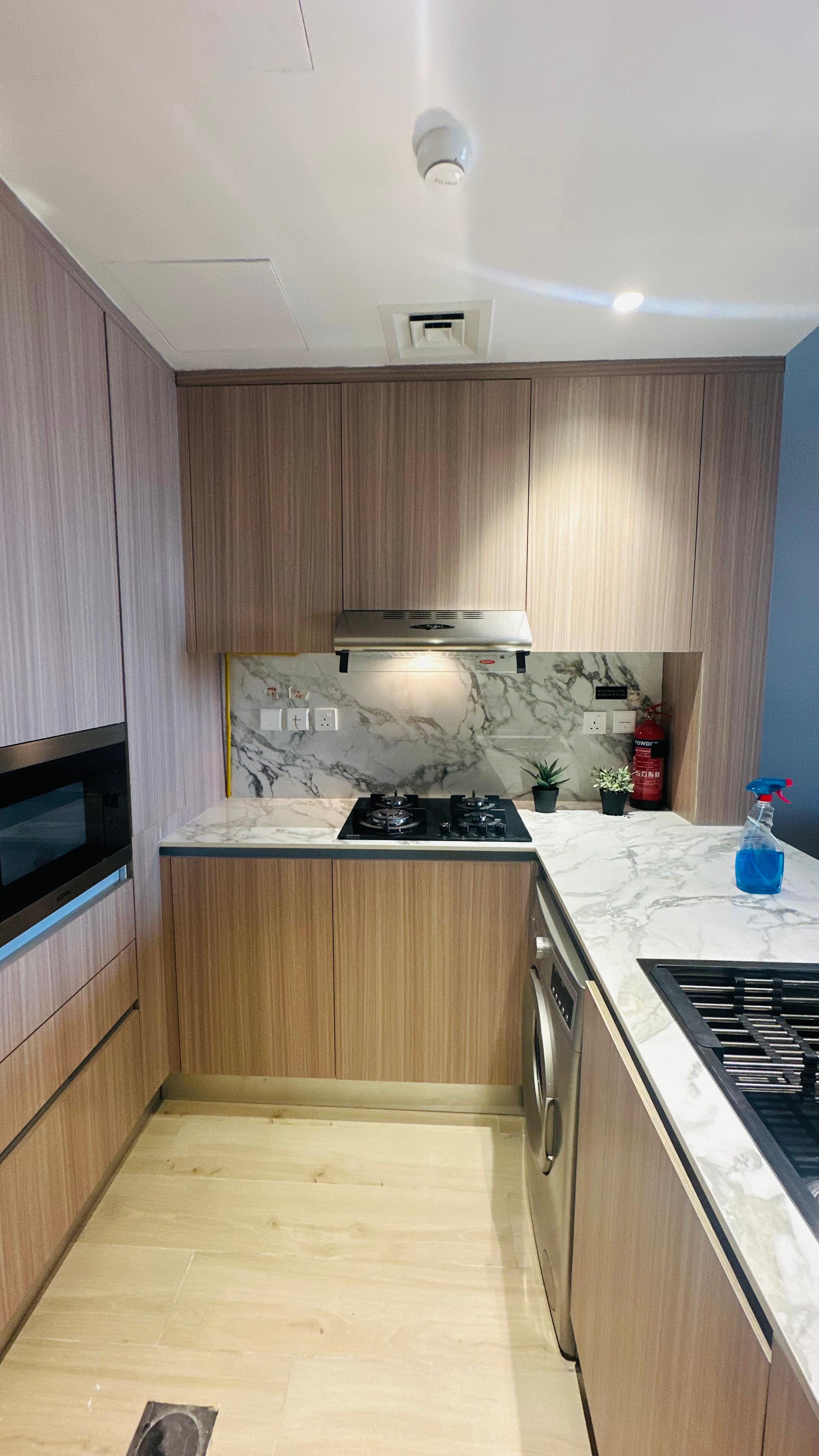 Renovated kitchen with light wood grain cabinetry, white marble worktops and backsplash, integrated stainless steel appliances