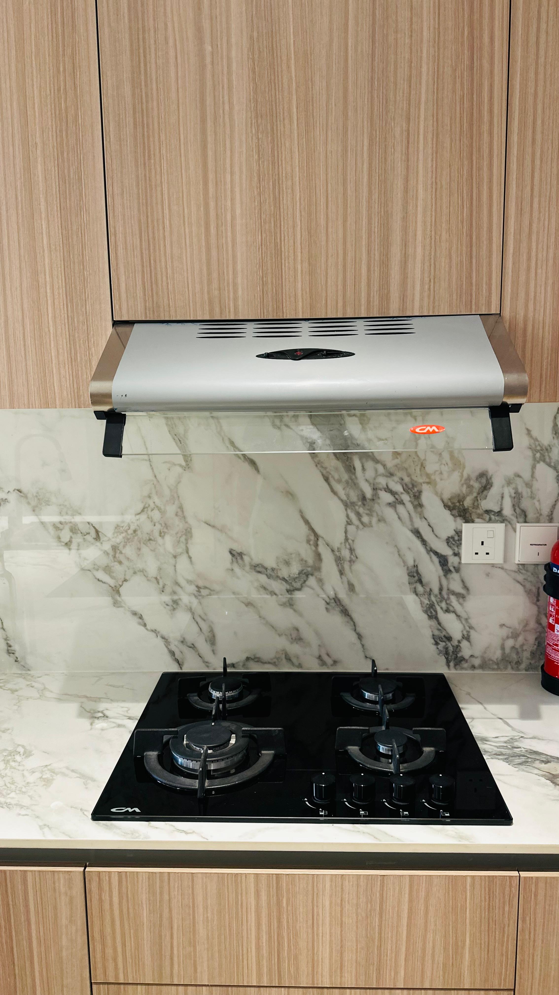 Light wood grain cabinetry and white marble backsplash above a black gas hob, a finish carried into bespoke wardrobe Dubai joinery