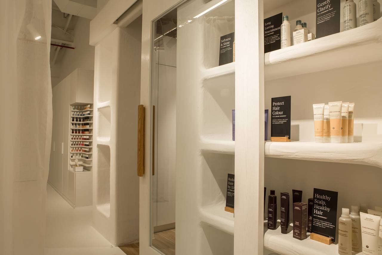Built-in white organically shaped shelving with a sliding glass front installed in a Dubai interior