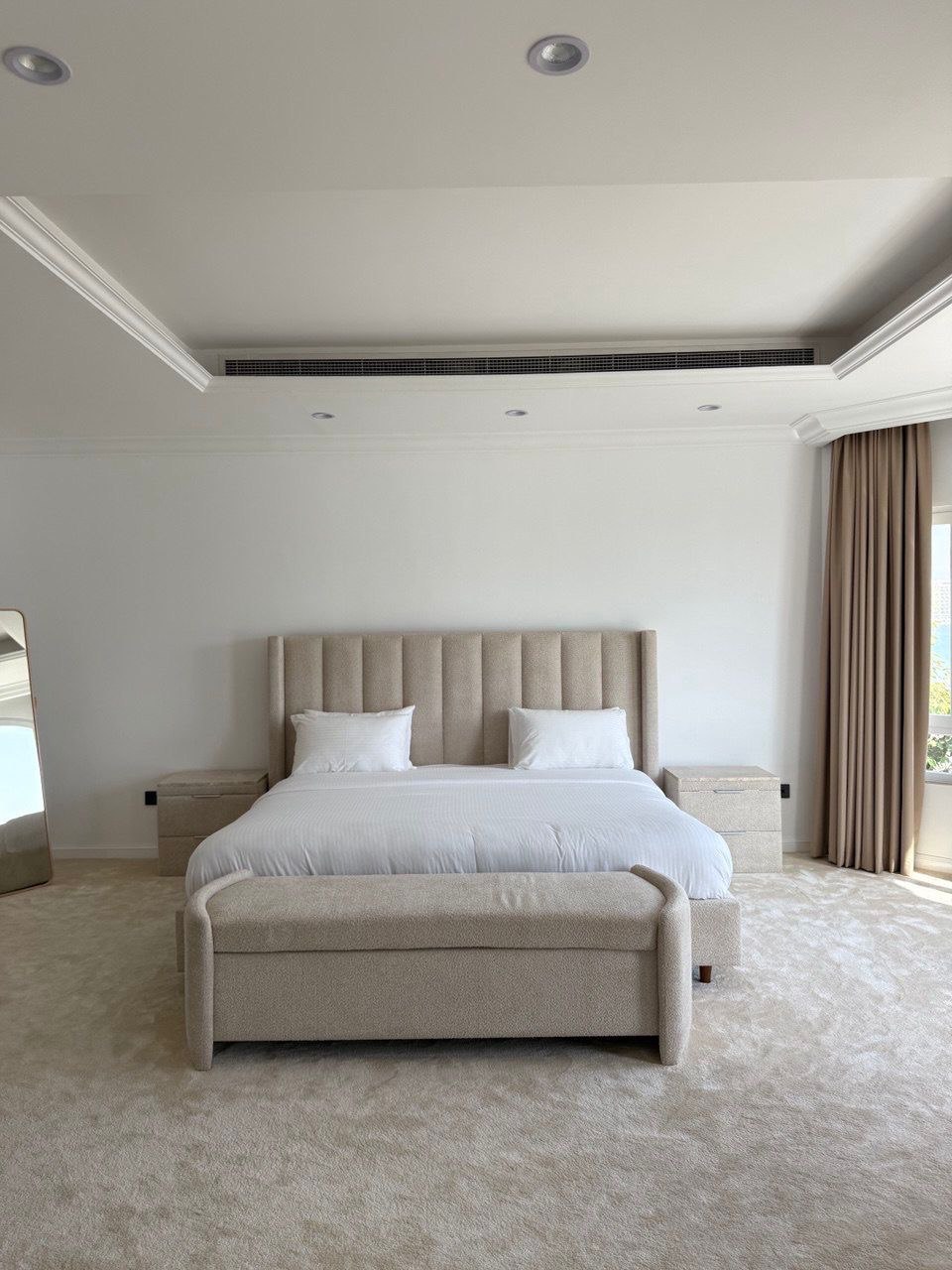 Minimalist bedroom with upholstered beige bed and clean white walls