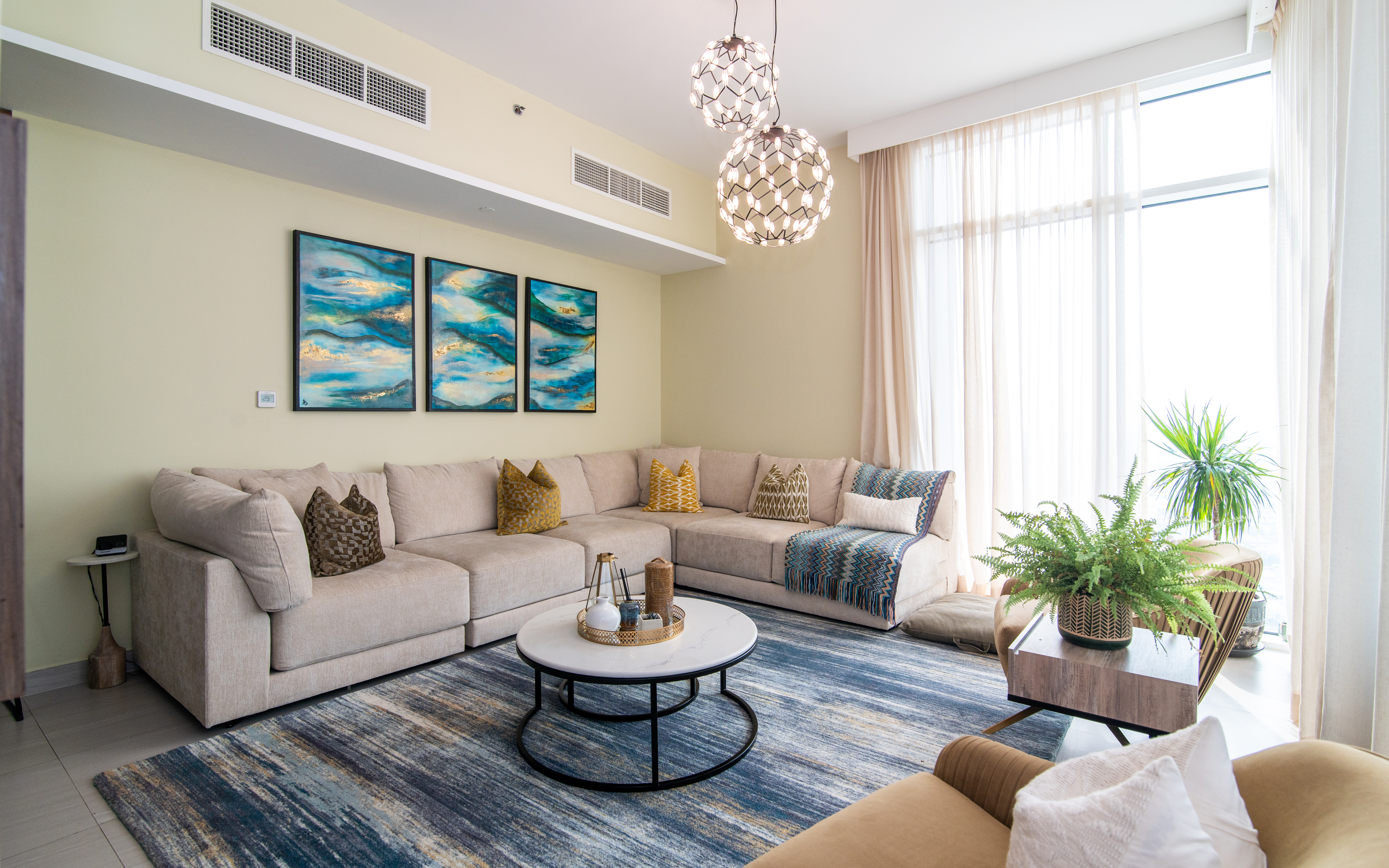 Modern living room with cream sectional, statement art and pendant lights