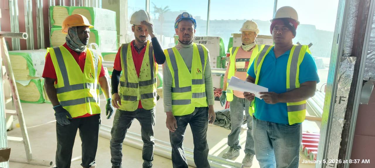 Five-person construction crew posing on interior fitout site