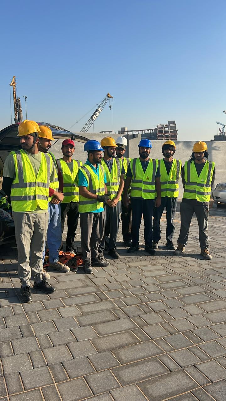 Construction workers in safety gear at outdoor site with cranes