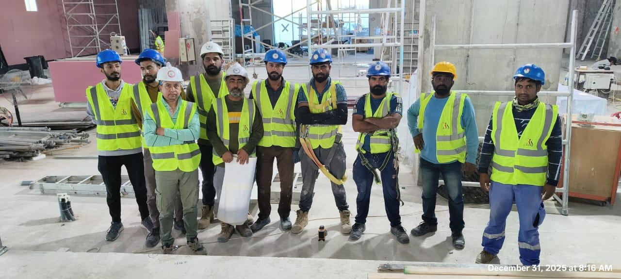10-person construction team in safety gear in large unfinished interior