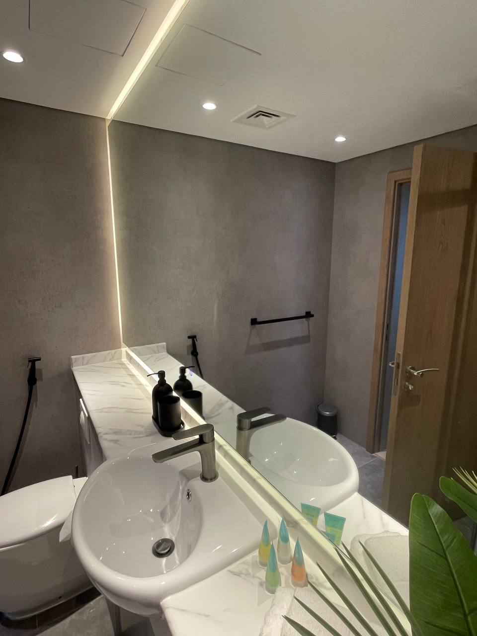 A well-lit, modern bathroom features a sleek white marble-patterned vanity with an integrated sink, contemporary chrome