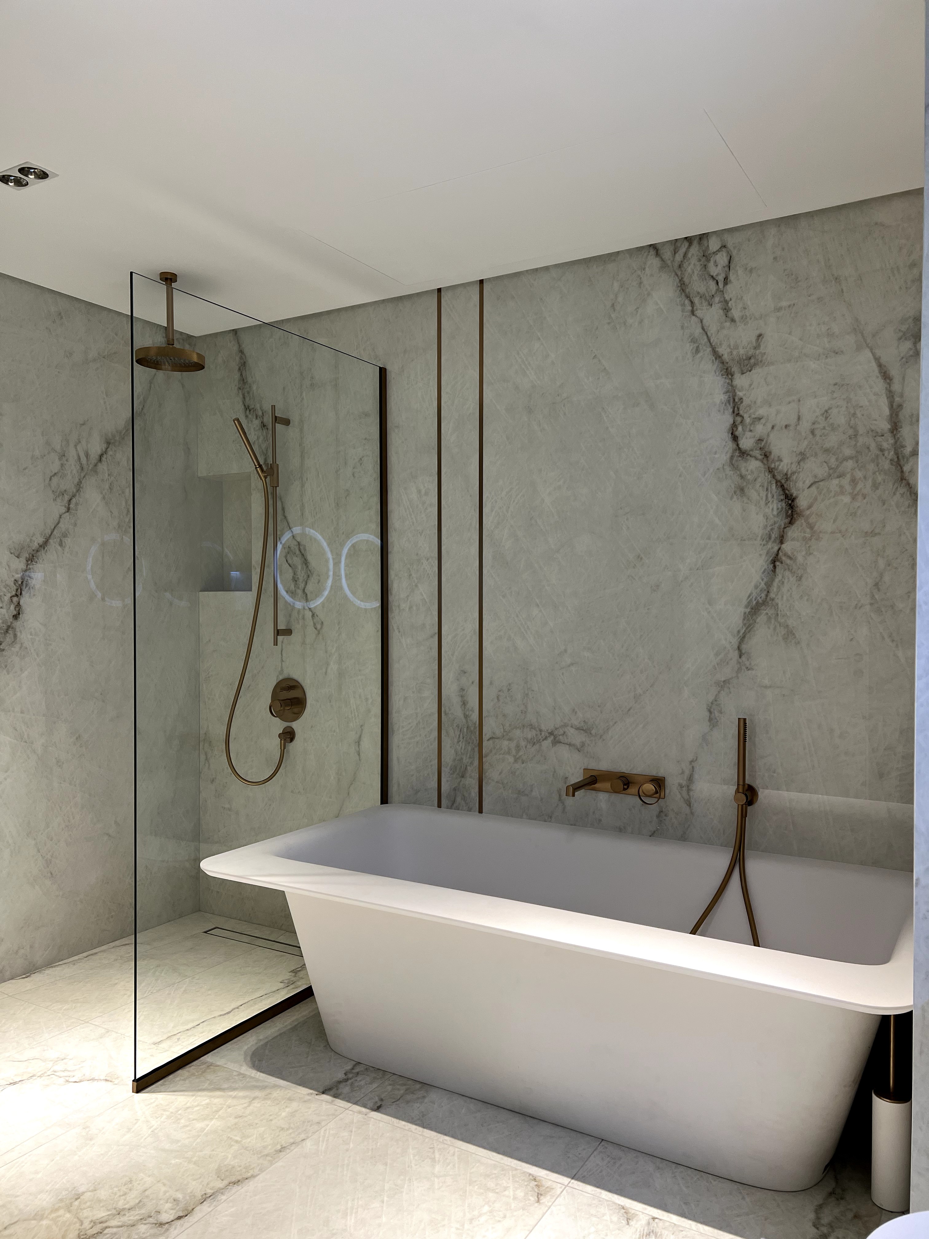 A luxurious and modern bathroom showcases a pristine white freestanding bathtub next to a glass-enclosed walk-in shower,