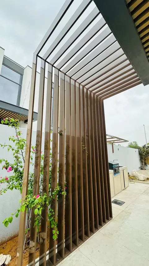 Modern brown metal slatted pergola with pink bougainvillea over light-tiled patio