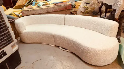 Cream boucle curved sofa in CLARE workshop, upholstery in progress