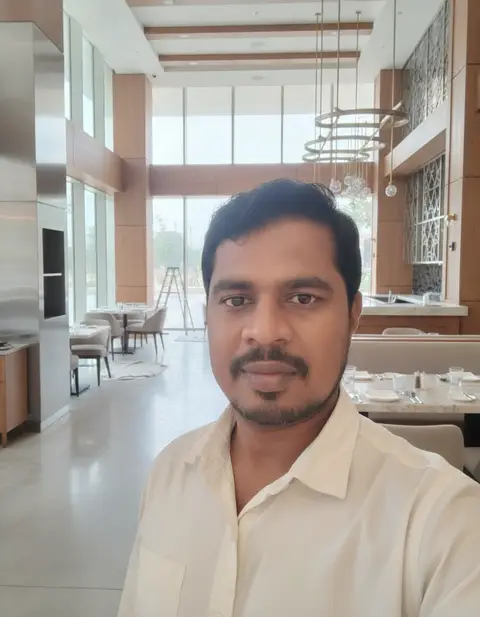 A man in a light-colored shirt takes a selfie, capturing a bright and spacious modern restaurant or — APEX STEEL WORKS L.L.C
