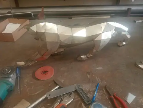 A striking geometric metal sculpture of a big cat, meticulously crafted from faceted metal panels — APEX STEEL WORKS L.L.C