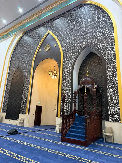 An intricately designed mosque interior featuring a wooden minbar, a mihrab with gold calligraphy, and walls — Malak Afzal