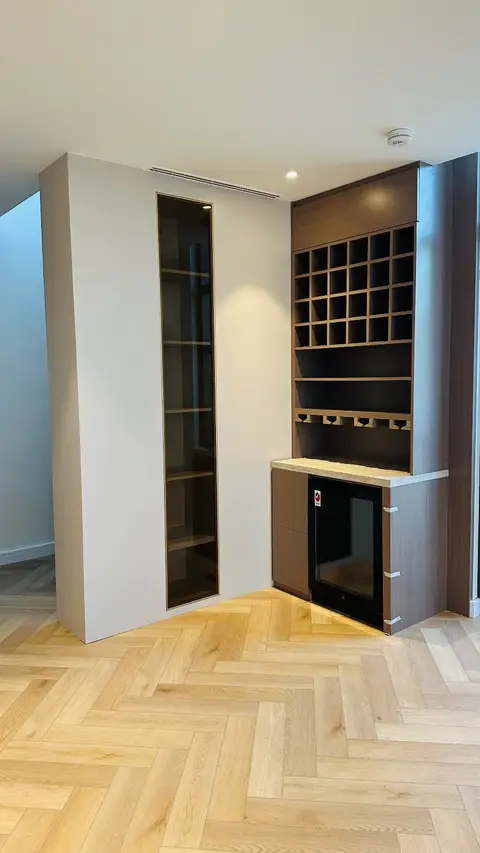 Custom dark wood built-in bar unit with wine cubbies and display cabinet