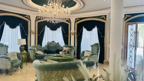 Classic villa living room with emerald green velvet seating and gold detailing, finished by CLARE