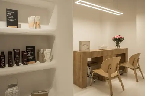 A minimalist beauty salon interior with a warm wooden consultation desk — CRAFTY CLARE DECORATION DESIGN L.L.C, Dubai