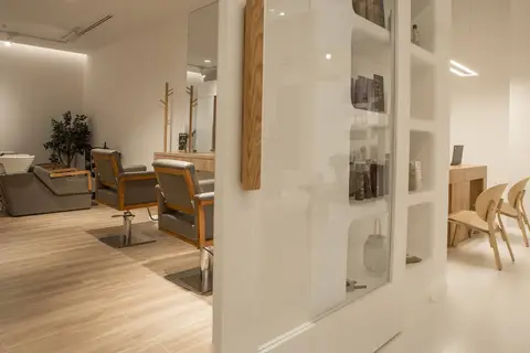 A modern hair salon interior features light wood-toned furniture, grey styling — CRAFTY CLARE DECORATION DESIGN L.L.C, Dubai