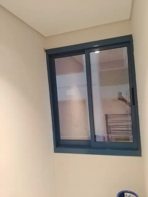 Modern aluminium sliding window with dark frame, reflecting interior