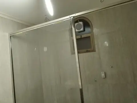 This progress shot captures a modern bathroom under renovation, featuring a sleek glass shower enclosure, light grey til