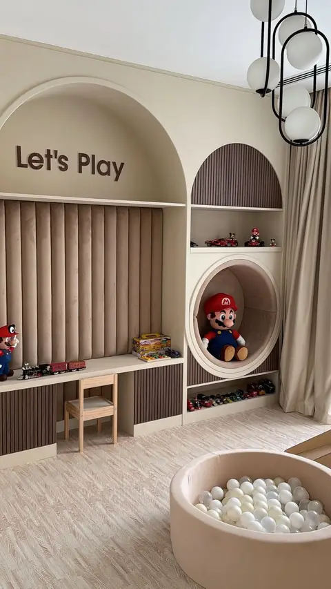 A beautifully designed children's playroom features extensive custom beige and brown built-in shelving with an — Dubai