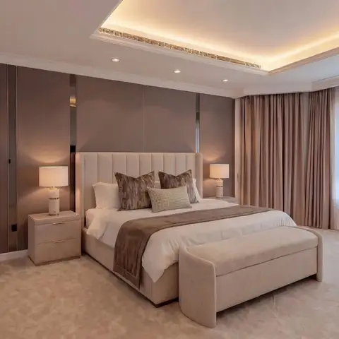 A luxurious and serene modern bedroom featuring an upholstered bed, matching nightstands with elegant lamps, textured wall