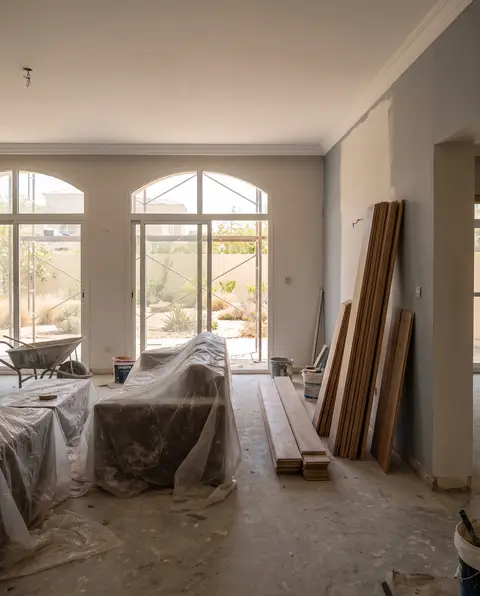 A wide shot of a spacious living room in Dubai undergoing renovation, featuring large arched sliding glass doors — Ali Mayed