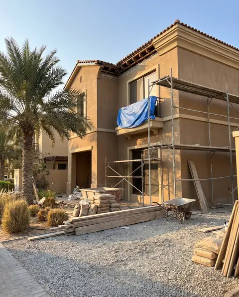 A two-story villa in Dubai/UAE is captured during its construction phase at golden hour, featuring scaffolding — Ali Mayed