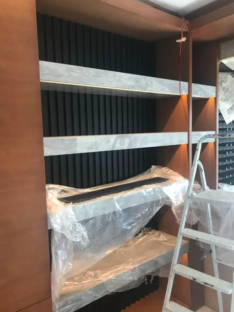 A modern built-in shelving unit featuring warm integrated LED lighting, light grey marble-effect — Chadi Baaklini, Dubai