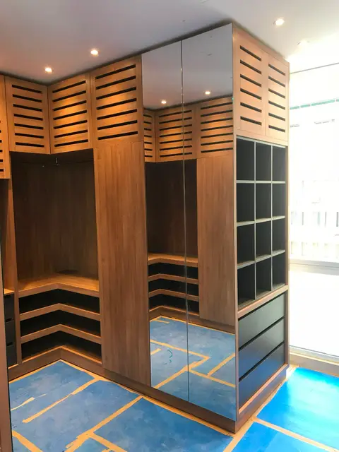 A newly installed, custom-built walk-in closet features warm wooden cabinetry with slatted upper — Chadi Baaklini, Dubai