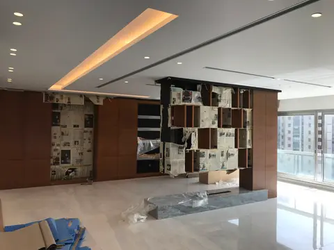 A modern living room undergoing renovation, featuring sleek wood paneling, a built-in shelving unit — Chadi Baaklini, Dubai