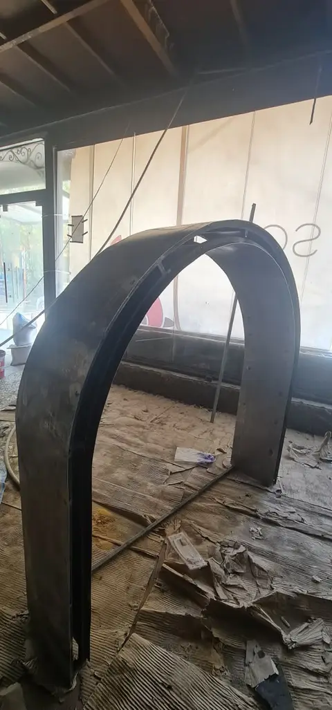 A large, dark, curved metal archway stands prominently in an unfinished interior space, with — Chadi Baaklini, Dubai