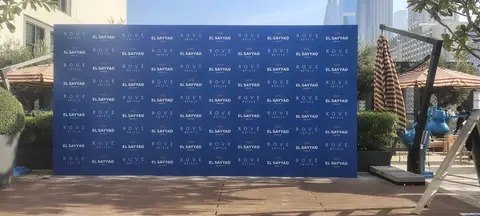 A large navy blue event backdrop with repeating 'ROVE HOTELS' and 'EL SAYYAD — MINGASH ENGRAVING & ORNAMENTATION WORKS EST.