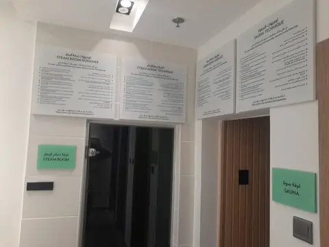 A freshly renovated spa hallway with clear bilingual guidance signs, a dark — MINGASH ENGRAVING & ORNAMENTATION WORKS EST.
