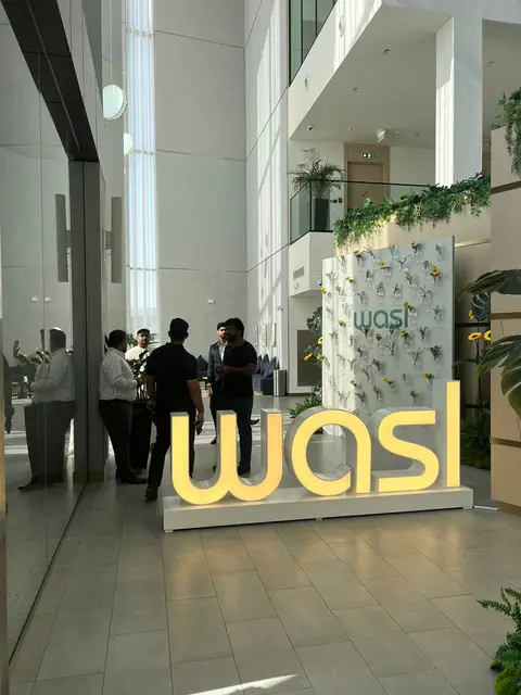 A bright, spacious modern lobby features illuminated floor and wall signage — MINGASH ENGRAVING & ORNAMENTATION WORKS EST.