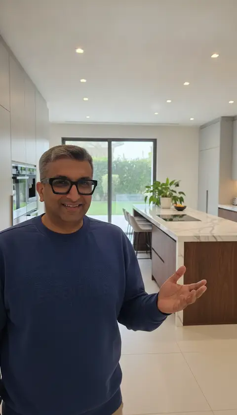 A smiling man in a navy "ESSENTIALS" sweatshirt gestures towards a — Lacasa Line Decoration Design And Fitout LLC, Dubai