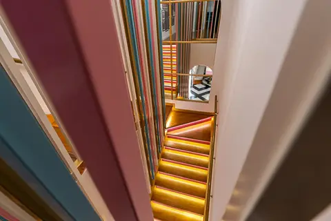 Illuminated wooden steps with warm LED lighting and a playful colorful slat railing reflect a geometric — Muhammed  Gani