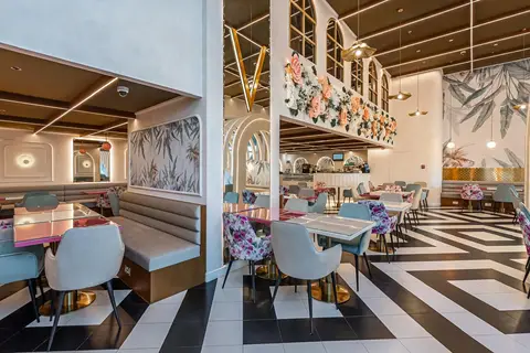 A vibrant restaurant interior featuring a black and white geometric floor, floral and solid upholstered — Muhammed  Gani