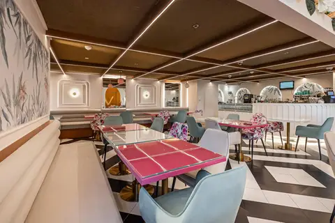 A playful modern cafe interior with glossy pink tabletops, light blue velvet chairs, and a black and white — Muhammed  Gani