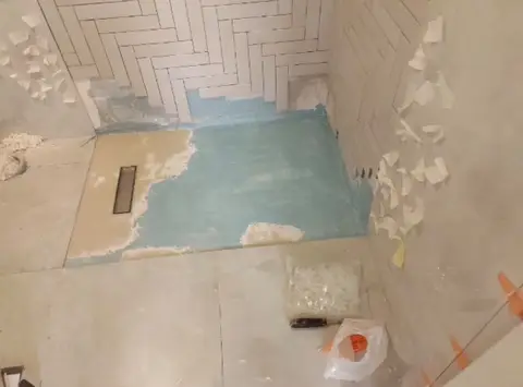 Bathroom shower renovation under way, featuring a blue waterproofing membrane, white subway tiles in a — A&B Design & Build