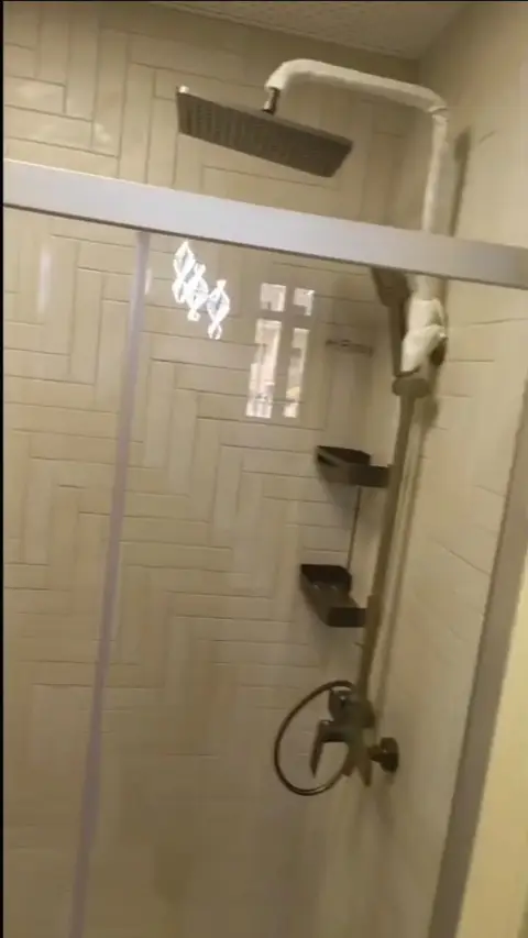 A modern shower enclosure with beige herringbone tiles, a rain shower head, handheld shower, and — A&B Design & Build