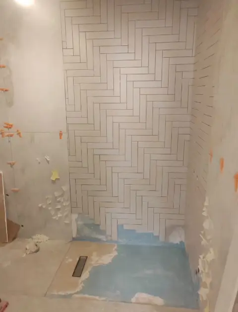 Bathroom renovation under way, featuring newly installed white herringbone shower wall tiles, visible — A&B Design & Build