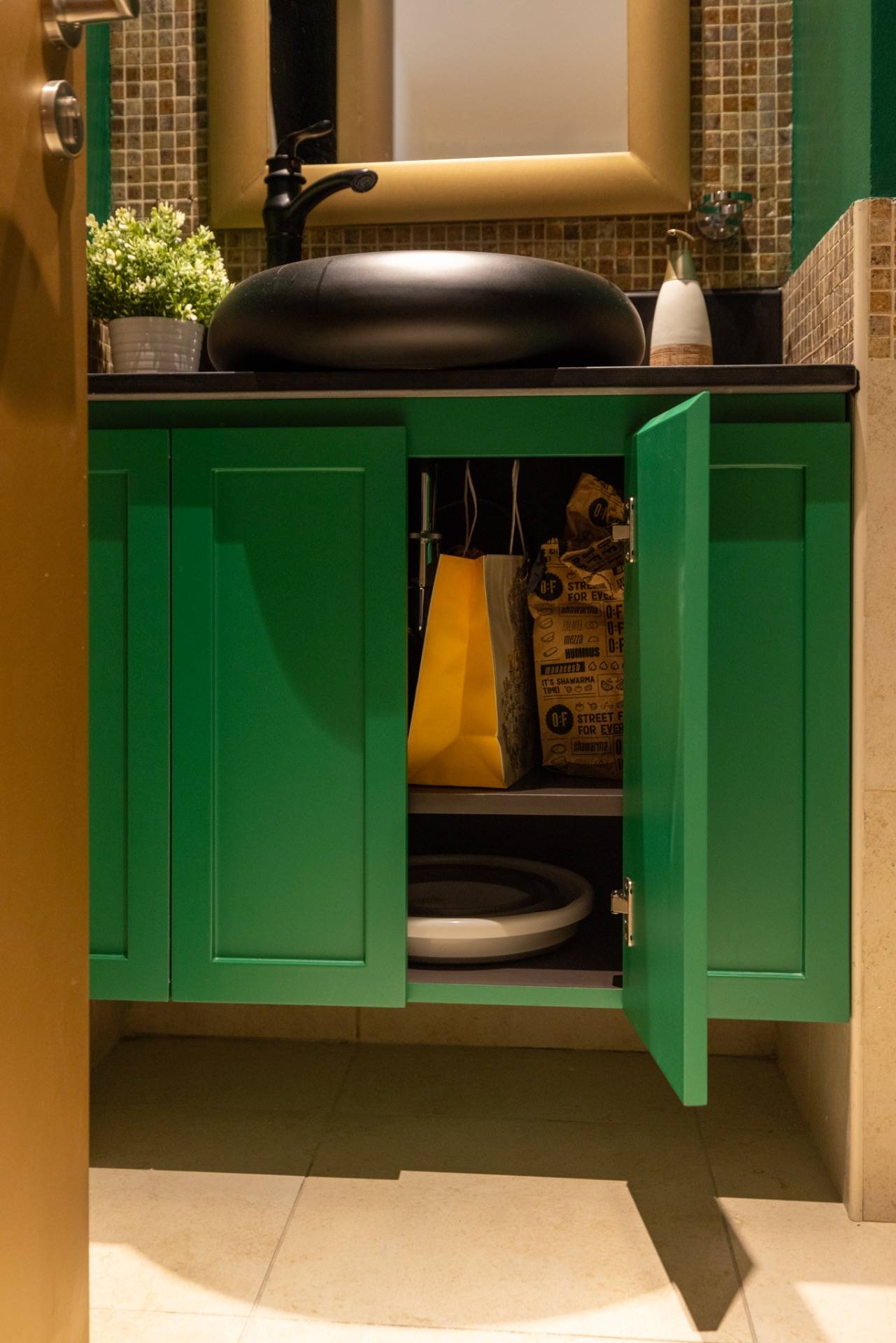 Custom floating bathroom vanity Dubai with bold emerald green shaker-style cabinets, a black oval vessel sink and matte black faucet against a mosaic tiled backsplash