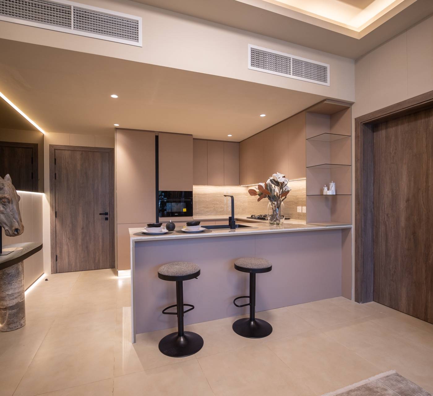 Sophisticated open plan kitchen and hallway with muted pink cabinetry, marble island and warm ambient lighting after a permitted Dubai villa fit-out