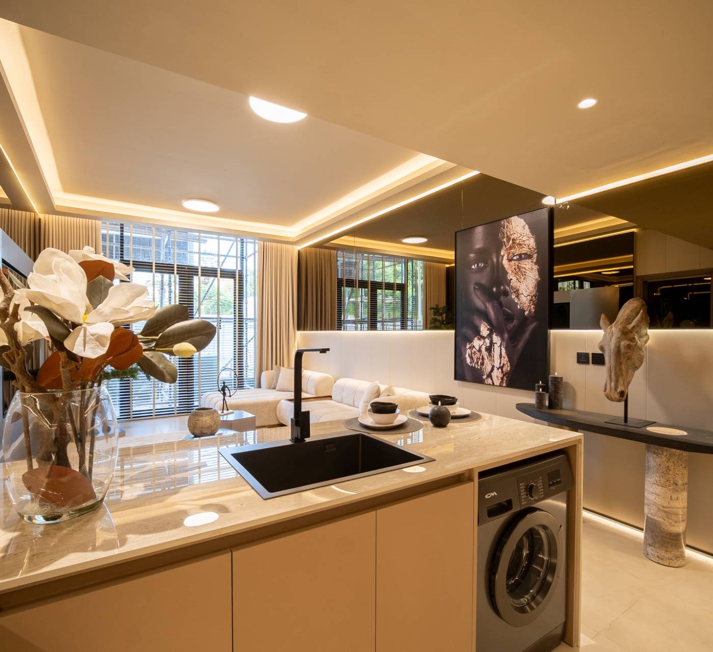 Open-plan kitchen and living area with marble island and mirrored wall, part of a villa expansion in Dubai.