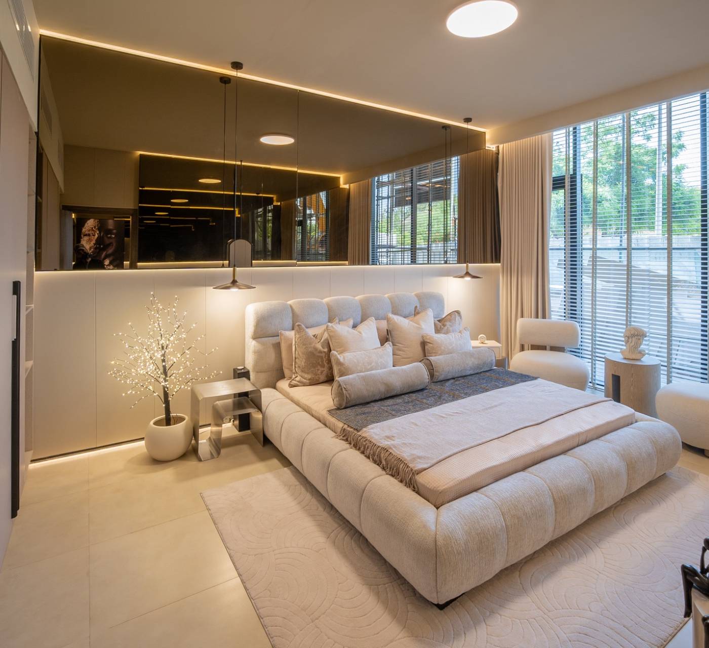 Luxurious master bedroom with upholstered bed and smoked mirror wall, a villa renovation by best villa contractors Dubai.