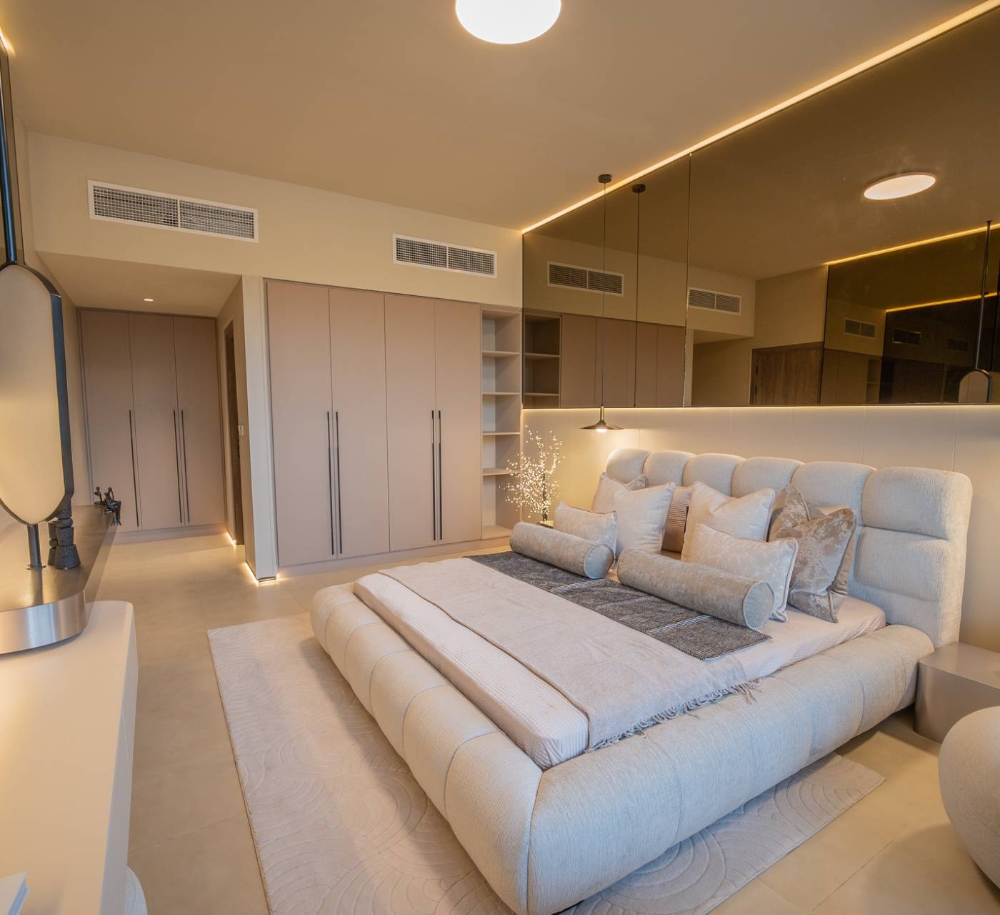 Modern bedroom with mirrored wardrobe wall and integrated warm lighting after a villa extension in Dubai.