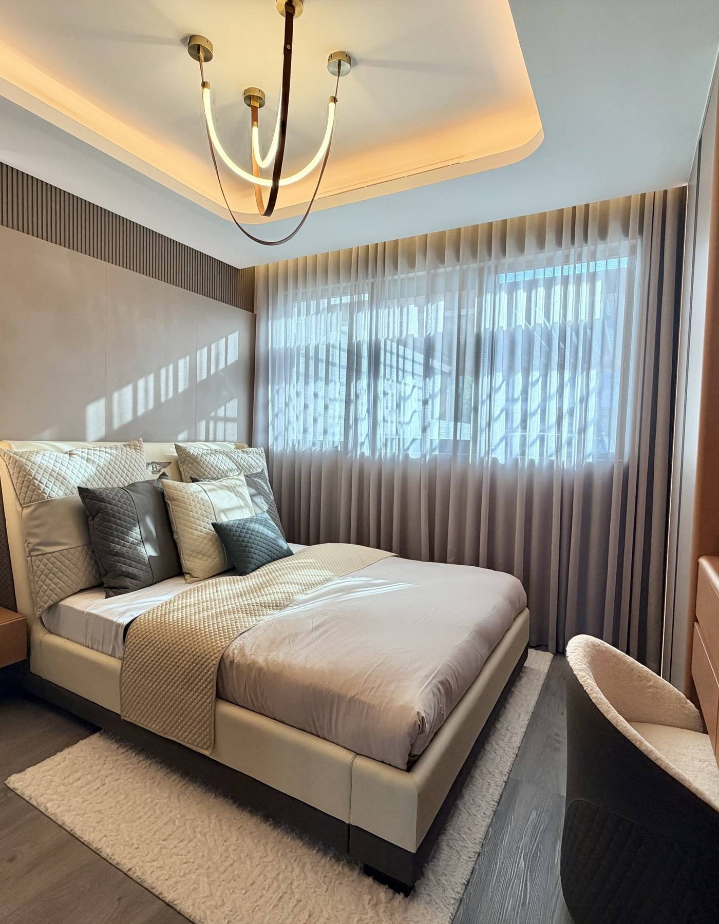 Luxurious Dubai master bedroom with a king size upholstered bed, warm cove lighting, brass chandelier, floating bedside table and fluted wall panelling, the kind of room where fitted wardrobes Dubai clients choose floor to ceiling builds.