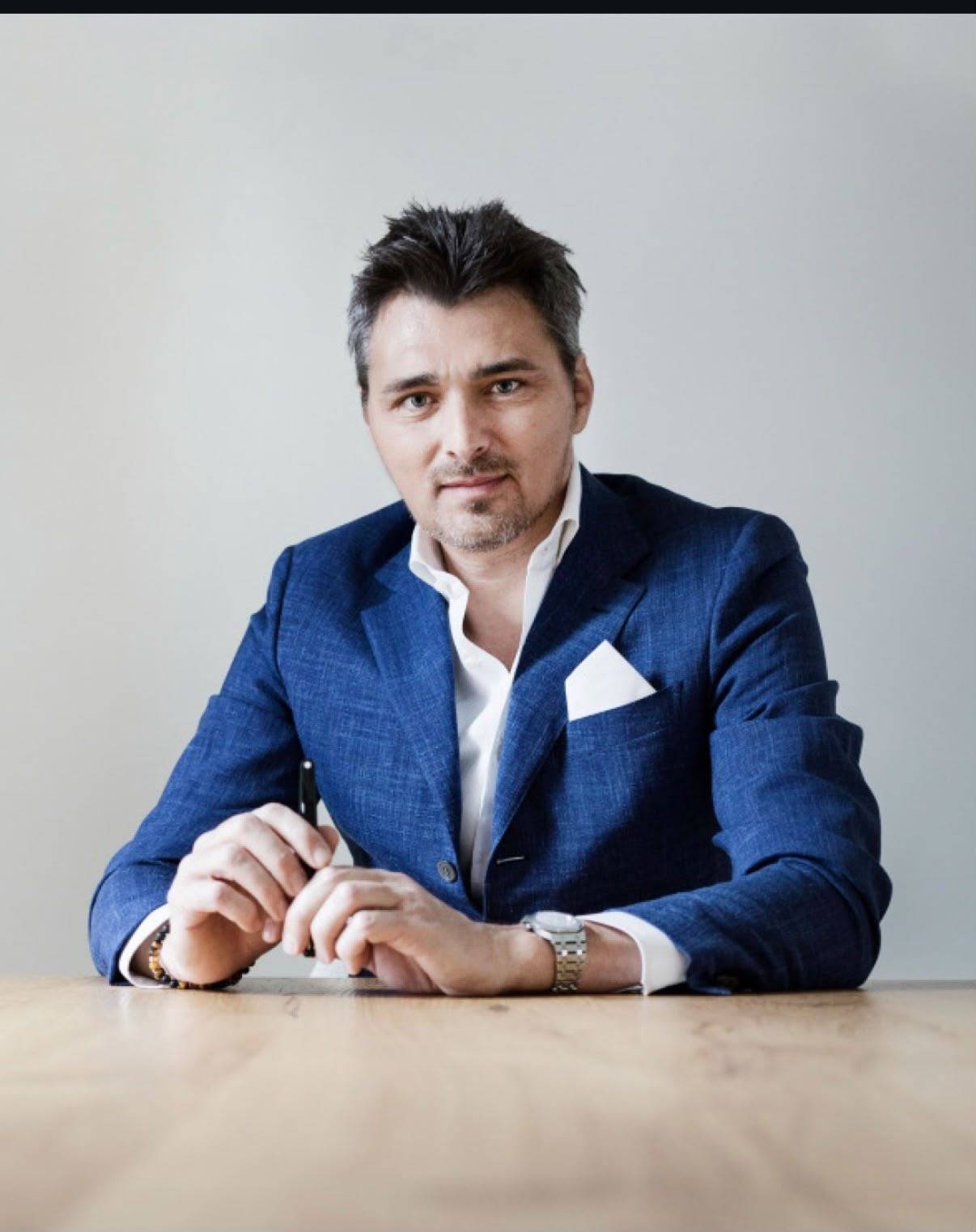 MODENZO team member seated at a light wooden desk in a blue blazer