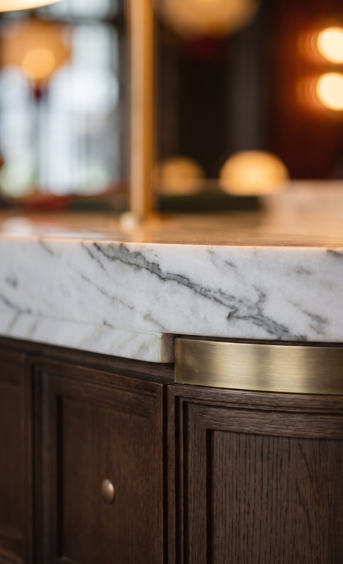 Detailed view of a marble-topped bar with elegant dark veining and polished brass trim fabricated by APEX Steel Works.