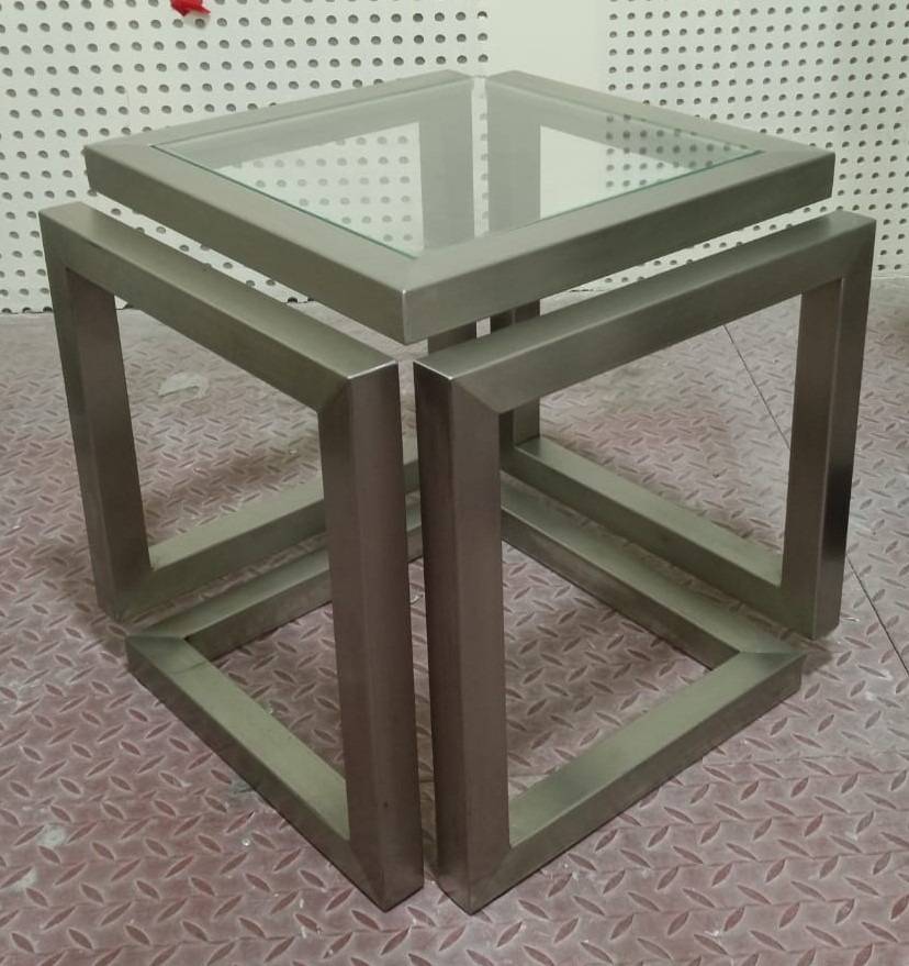 A brushed metal geometric side table with clear glass top and industrial backdrop from APEX <a href=