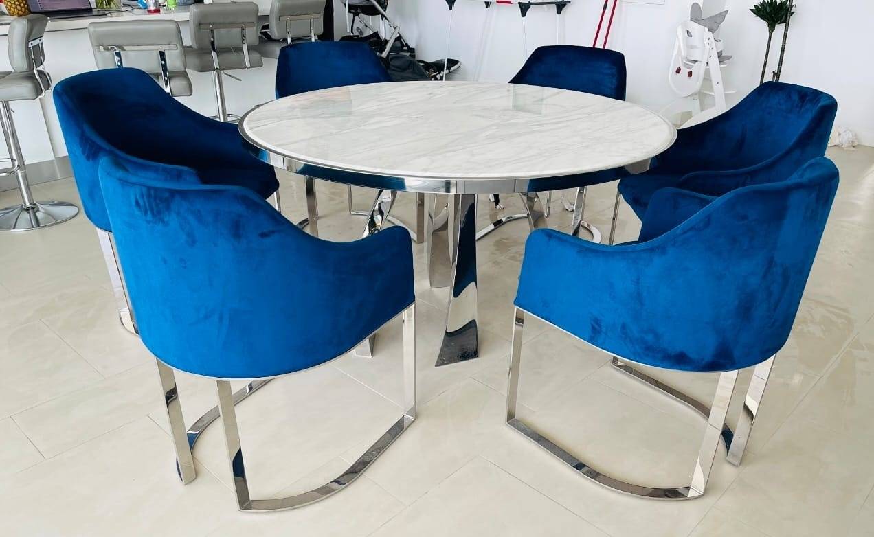 Steel fabrication Ajman custom furniture project showing a white marble top dining table with polished chrome base and chrome cantilever chairs